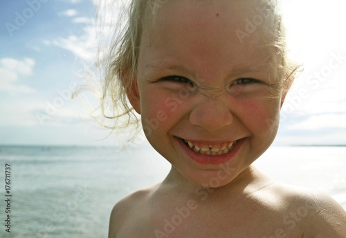 Little girl laughs against the sea. 