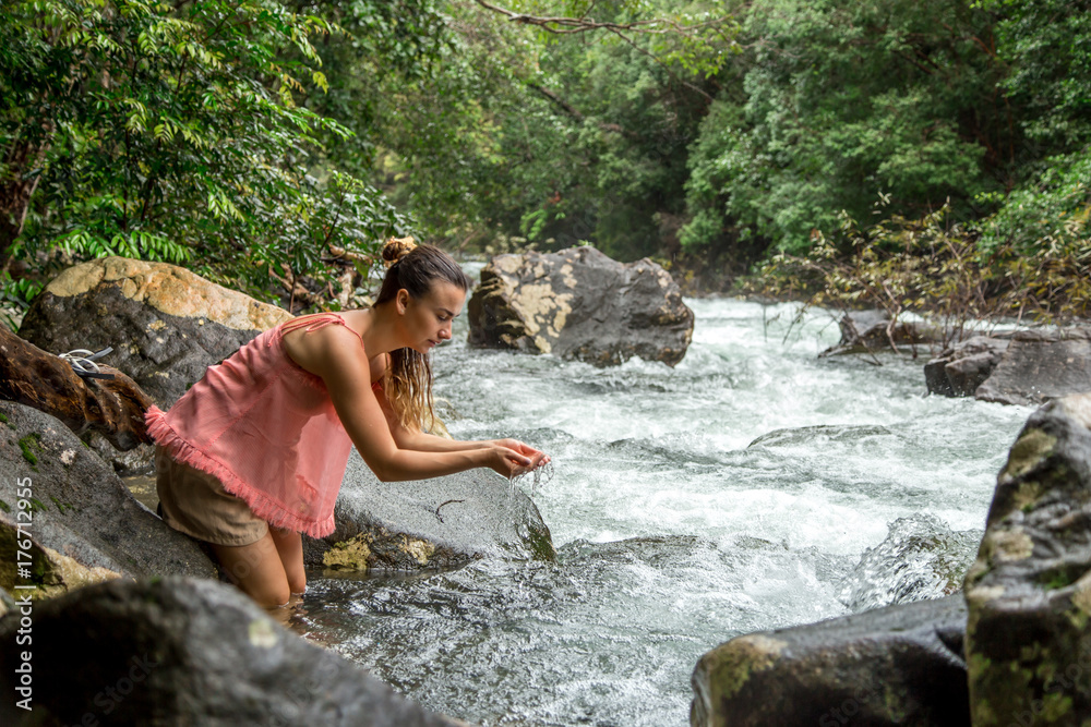 the girl drinks water from a mountain stream the girl drinks water from a mountain stream