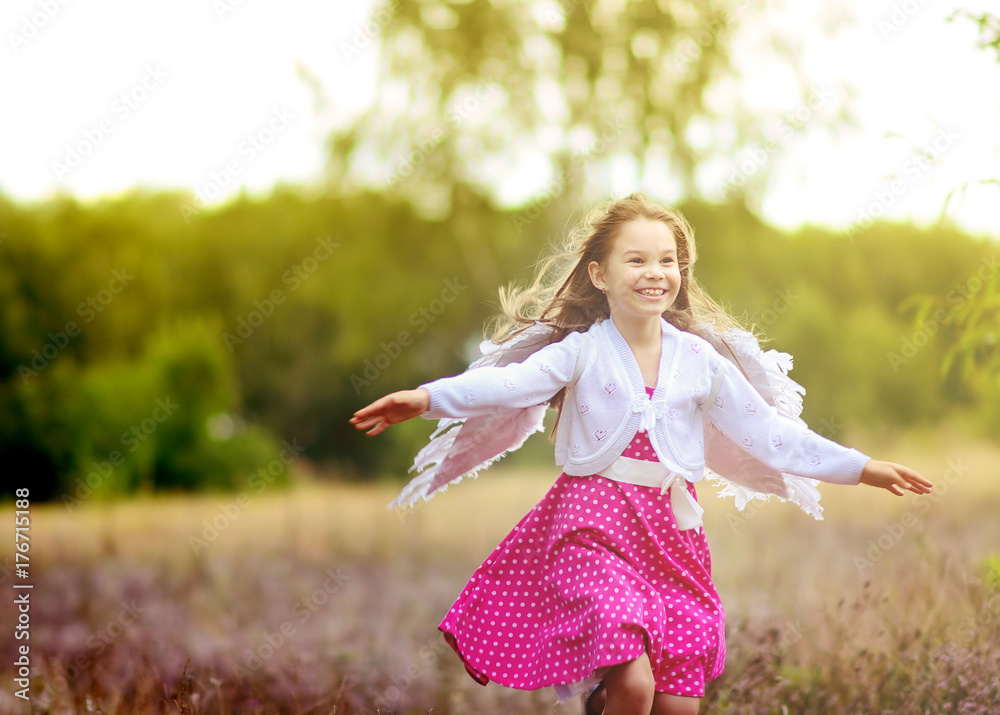 beautiful cheerful girl with angel wings running around the field at sunset.
