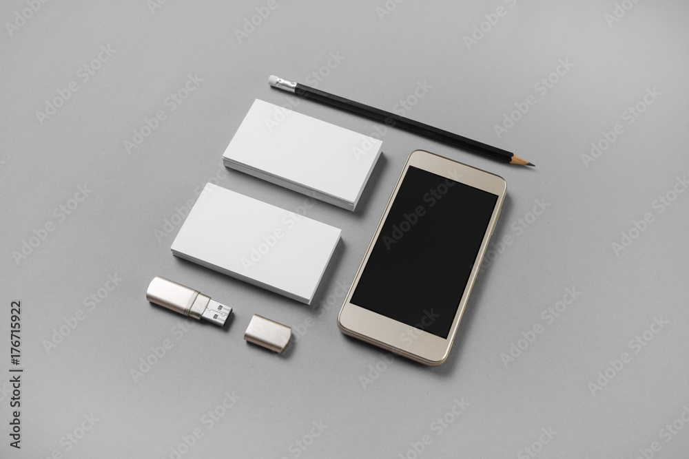 Gadgets and stationery. Mockup of blank business cards, pencil, usb flash drive and cellphone with blank screen on gray paper background. Gadgets and stationery. Mockup of blank business cards, pencil, usb flash drive and cellphone with blank screen on gray paper background.