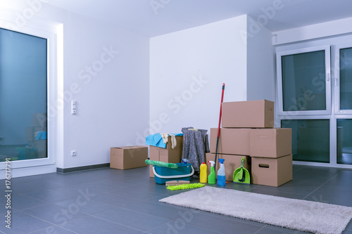 Helle, leere Luxuswohnung mit Kartons und Putzmittel auf schwarzem Fliesenboden