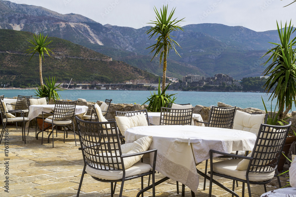 Restaurant in the open air near the sea. Tables and chairs on a stone terrace without people. Budva. Montenegro