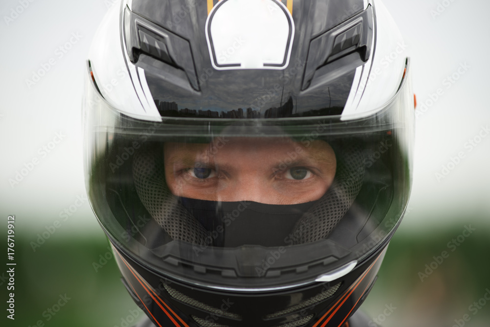 Close up shot of blue eyed Caucasian male wearing stylish motorcycle helmet, staring at camera with confident determined look before race. People, extreme sports, active lifestyle, speed and adrenalin