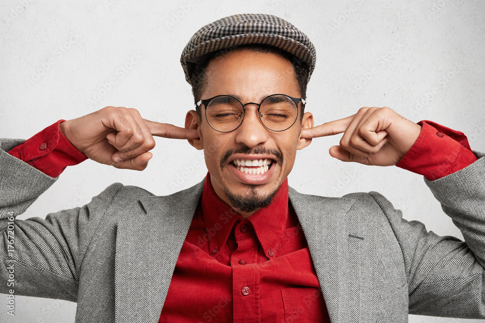 Φωτογραφία Funny bearded guy wears old fashionable clothes, plugs ears as ignores wife`s remarks and orders, feels excited