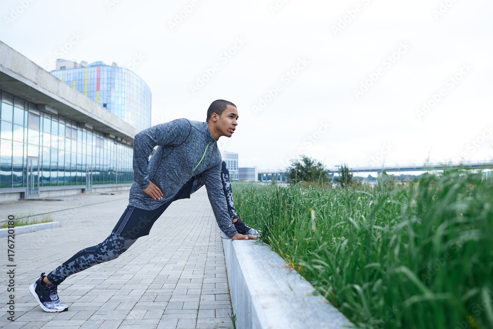 Healthy active lifestyle, people, sports and fitness concept. Profile view  of muscular attractive male warming up legs muscles before exercise session  or running workout in urban surroundings Stock Photo | Adobe Stock