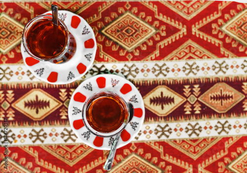Close-Up of delicious Red Turkish tea with traditional pear shaped glass on ethno patterned tablecloth in cafe © EdNurg