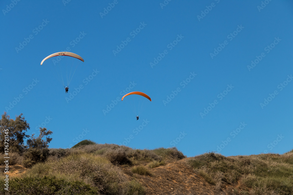 Two paragliders in the air, above a meadow Two paragliders in the air, above a meadow