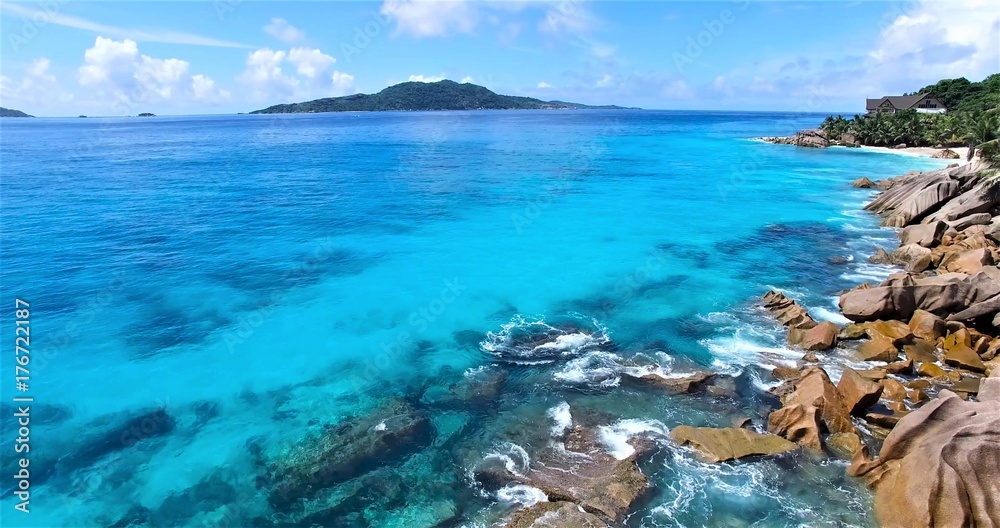 the transparent turquoise sea with Wave of the sea on the rocky beach against blue sky
