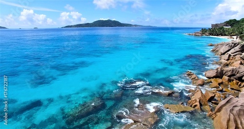 the transparent turquoise sea with Wave of the sea on the rocky beach against blue sky