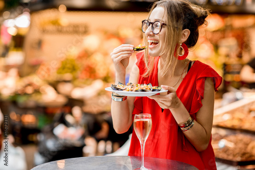 Photography Young woman in red dress having lunch with mussels and rose wine sitting at the