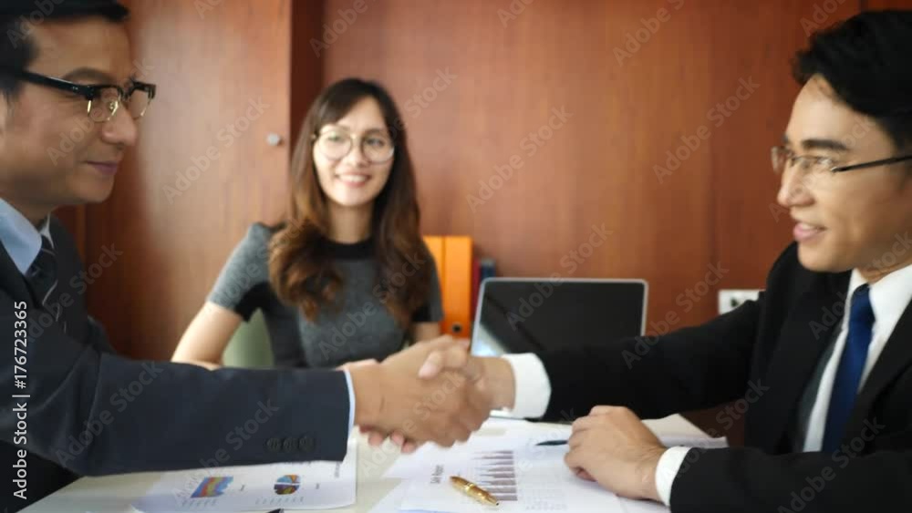 Mature businessman shaking hands to seal a deal with his partner and colleagues in office. Mature businessman shaking hands to seal a deal with his partner and colleagues in office.