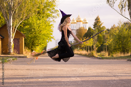 Photography Joyful girl in witch costume flies on broomstick