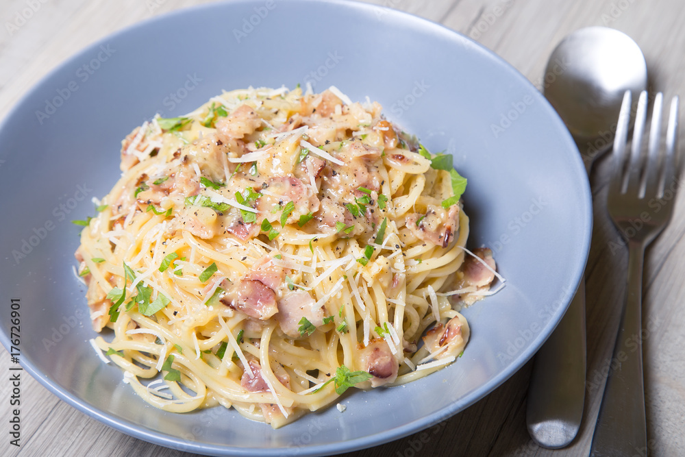 Pasta carbonara with bacon, cheese and parsley. Traditional Italian dish. Close-up, selective focus.