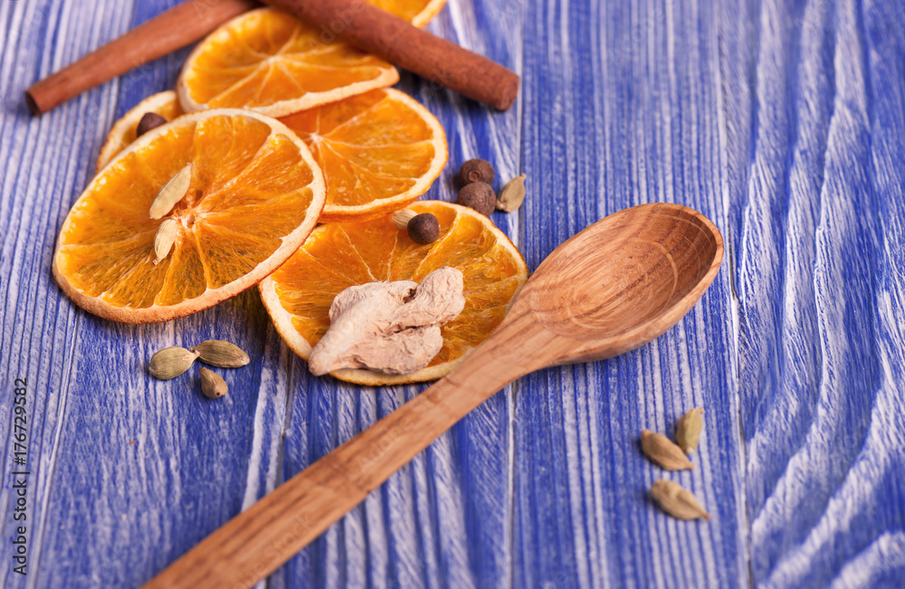 Dry slices of orange, cinnamon, ginger and cardamom, on a blue wooden background. Aromatic spices. Christmas decorations. Dry slices of orange, cinnamon, ginger and cardamom, on a blue wooden background. Aromatic spices. Christmas decorations.