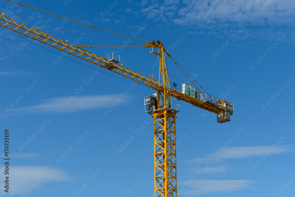 yellow tower crane against the blue sky with clouds