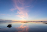 Evening sunlight on coast, pink clouds, blue sky reflection on water. Beach in summer. Seaside natural environment. Shore in Kesselaid, small island in Estonia. Nature Reserve in North Europe