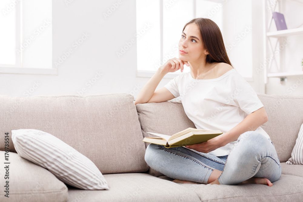 Young brunette woman reading the book at home on the couch. Young brunette woman reading the book at home on the couch.