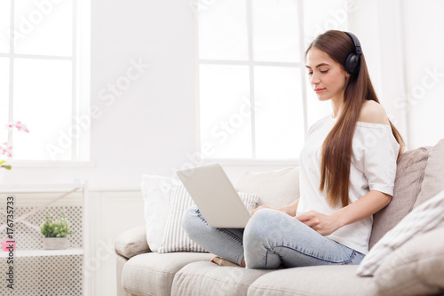 Young women in headphones listening to music and using laptop