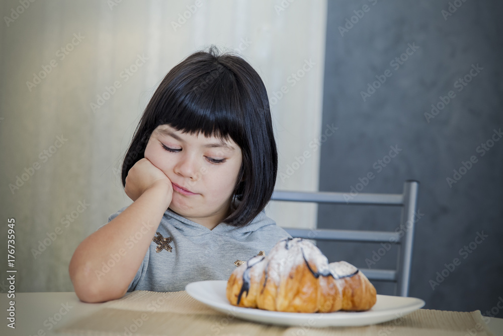 Cute black hair little girl looking at croissant Cute black hair little girl looking at croissant