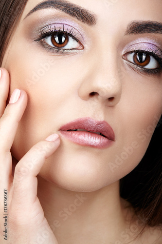 Close-up portrait of  big-eyed young brunette woman  with hand near face