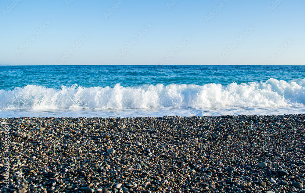 Waves breaking on a stony beach, forming sprays Waves breaking on a stony beach, forming sprays