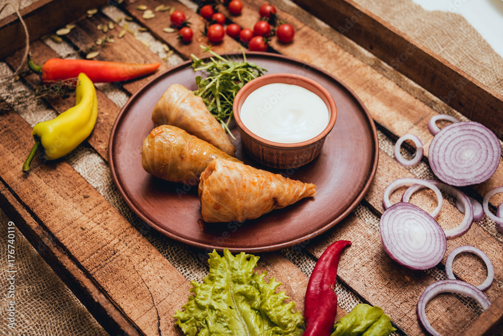 Tasty meat rolls with sour cream and salad on wooden table