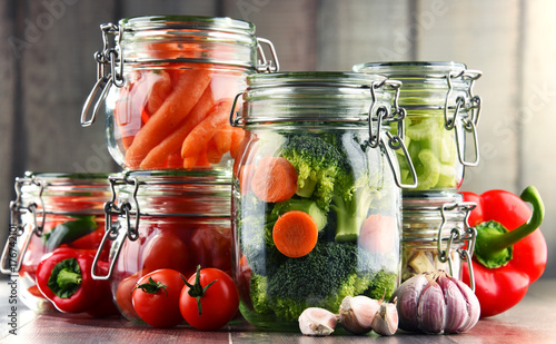 Jars with marinated food and organic raw vegetables