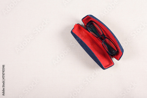 eyeglass and red boxed on fabric background.