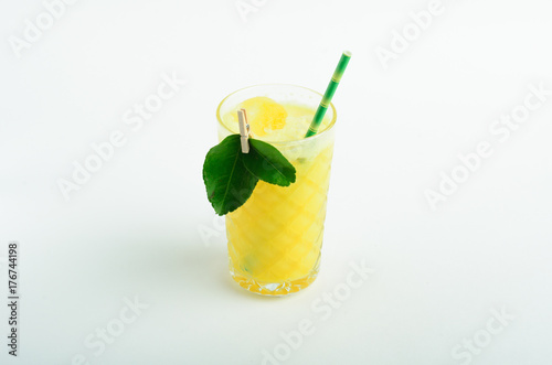 Yellow lemonade with ice decorated leaves in glass isolated on white background
