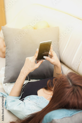 Young woman playing smart phone lying in sofa