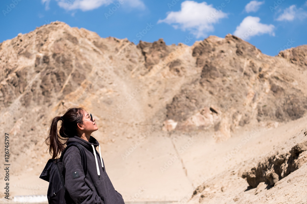 Fototapeta premium Portrait image of a beautiful Asian woman tourist standing in front of mountain and blue sky background