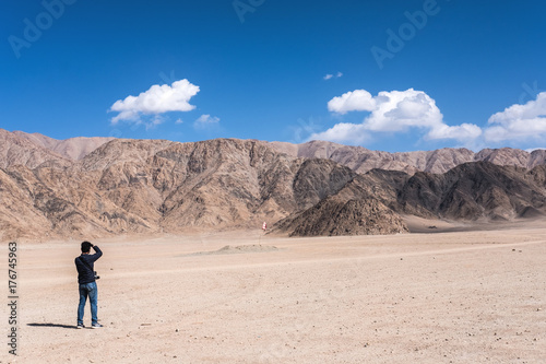A man photographer taking a landscape photo of mountains and blue sky in Ladakh , India