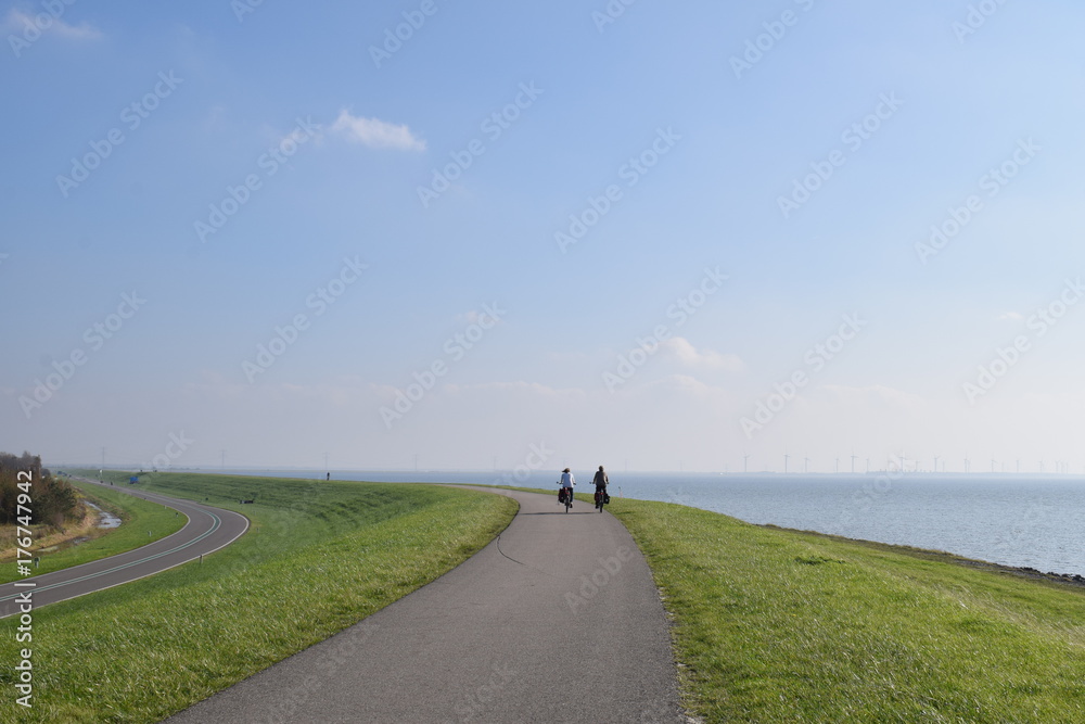 Obraz premium Typical dutch image of people cycling on the dike