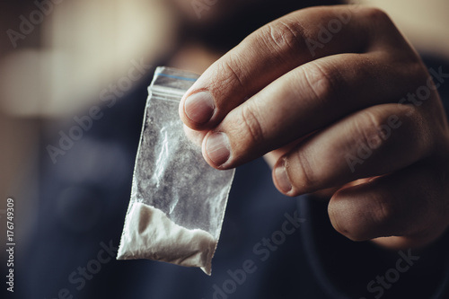 Man hand holds plastic packet or bag with cocaine or another drugs, drug abuse and danger addiction concept photo