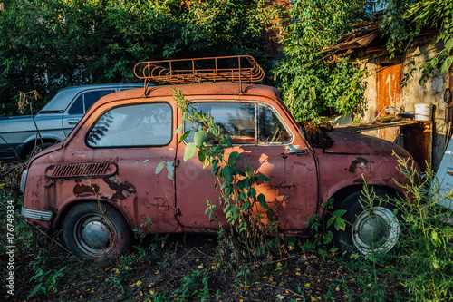 Old rusty overgrown abandoned red soviet retro car