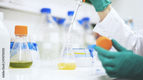 Close up of ladyscientist s hands taking some yellow liquid to examine under a microscope.