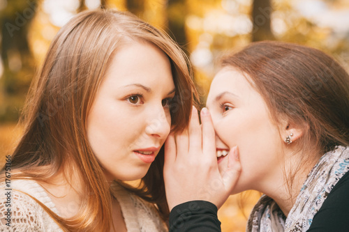 woman telling secret to her friend