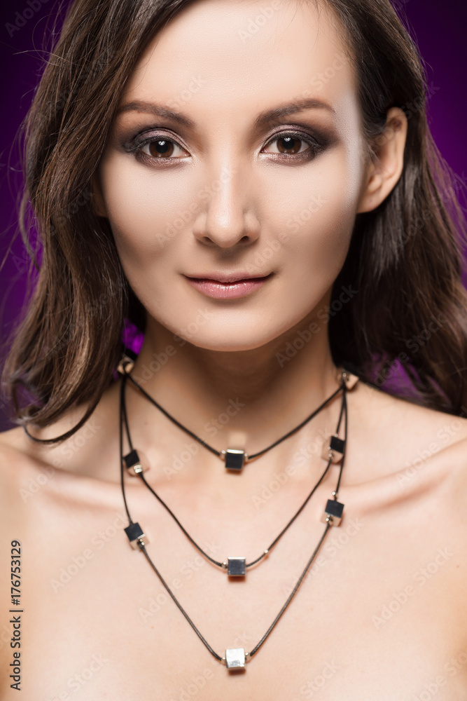 The beautiful girl wearing a necklace on a violet background