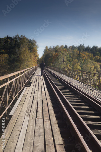 a lonely unidentified man walks over the old train bridge