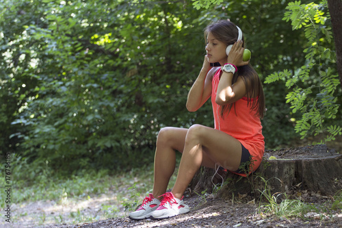Young girl with headphones sitting at the lodge and relax after jogging