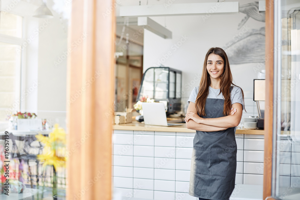 Young lady entrepreneur running a successful small cafe. Standing in front of coffee machine with arms crossed. Young lady entrepreneur running a successful small cafe. Standing in front of coffee machine with arms crossed.