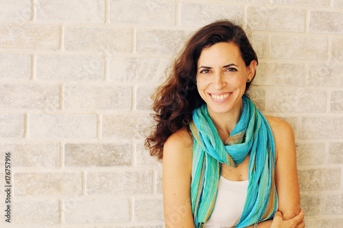 Portrait of smiling beautiful woman in turquoise skirt standing against of city grey wall