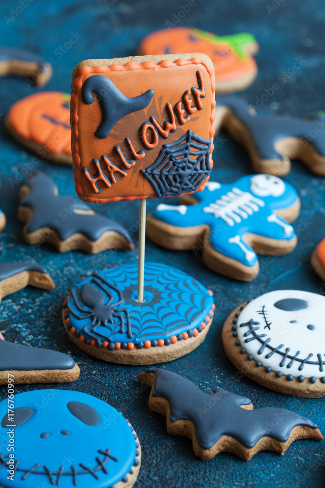 Homemade gingerbread cookies in the form as Halloween skeletons, jack-o-lantern pumpkins, ghost and bats on the wooden table. Space for text and selective focus.