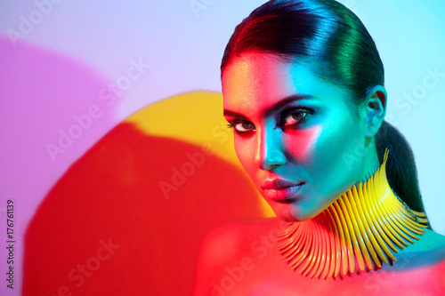 Fashion model woman in colorful bright lights posing. Portrait of beautiful sexy girl with trendy makeup photo