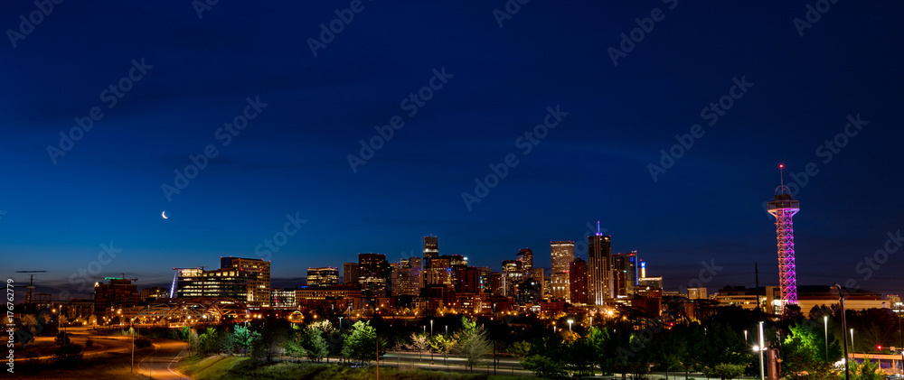 Full skyline of Denver Colorado at night with a moon