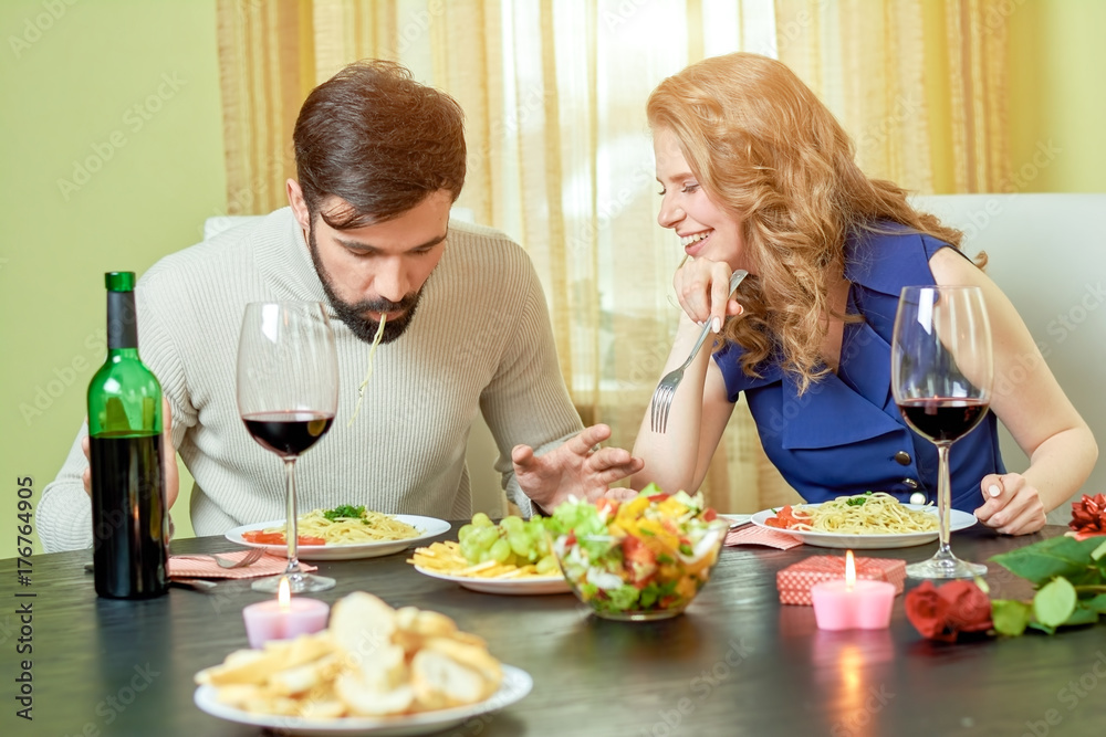 Young couple eating. Food and wine on table. What to order in restaurant.