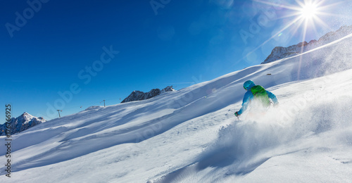 Young man skier running downhill in powder snow