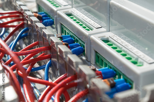 Electric wire laid in the cable channel is connected to the electronic devices. Connect wires to modular metering devices on a mounting panel in electrical closet. Red wire and blue with the tips.