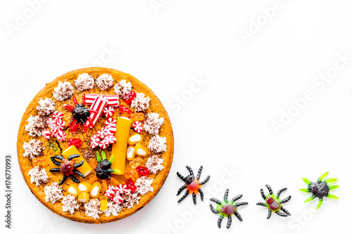 Gummy spiders crawls toward pie for halloween on white background top view copyspace