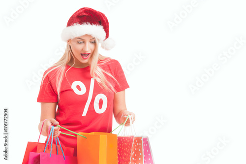  happy young woman with santa hat carrying shopping bags